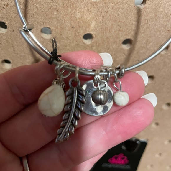 Silver bangle bracelet with a feather, discs, and white crackle stones.